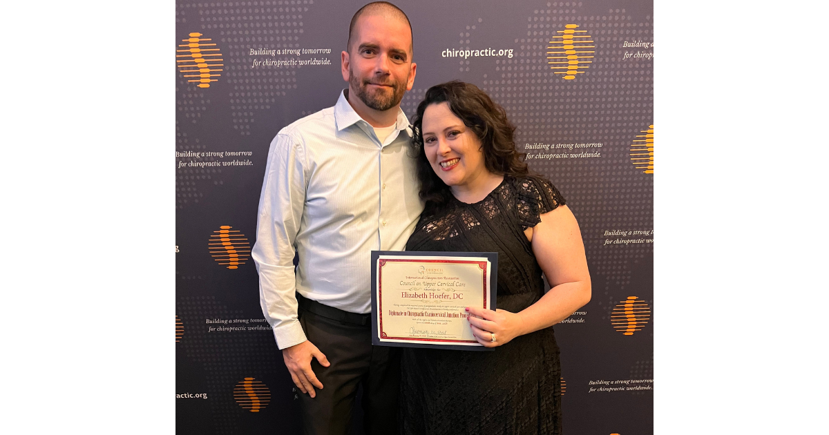 Dr. Elizabeth Hoefer and her husband Michael holding her Diplomate in Chiropractic Craniocervical Junction Procedures certificate at an awards ceremony.