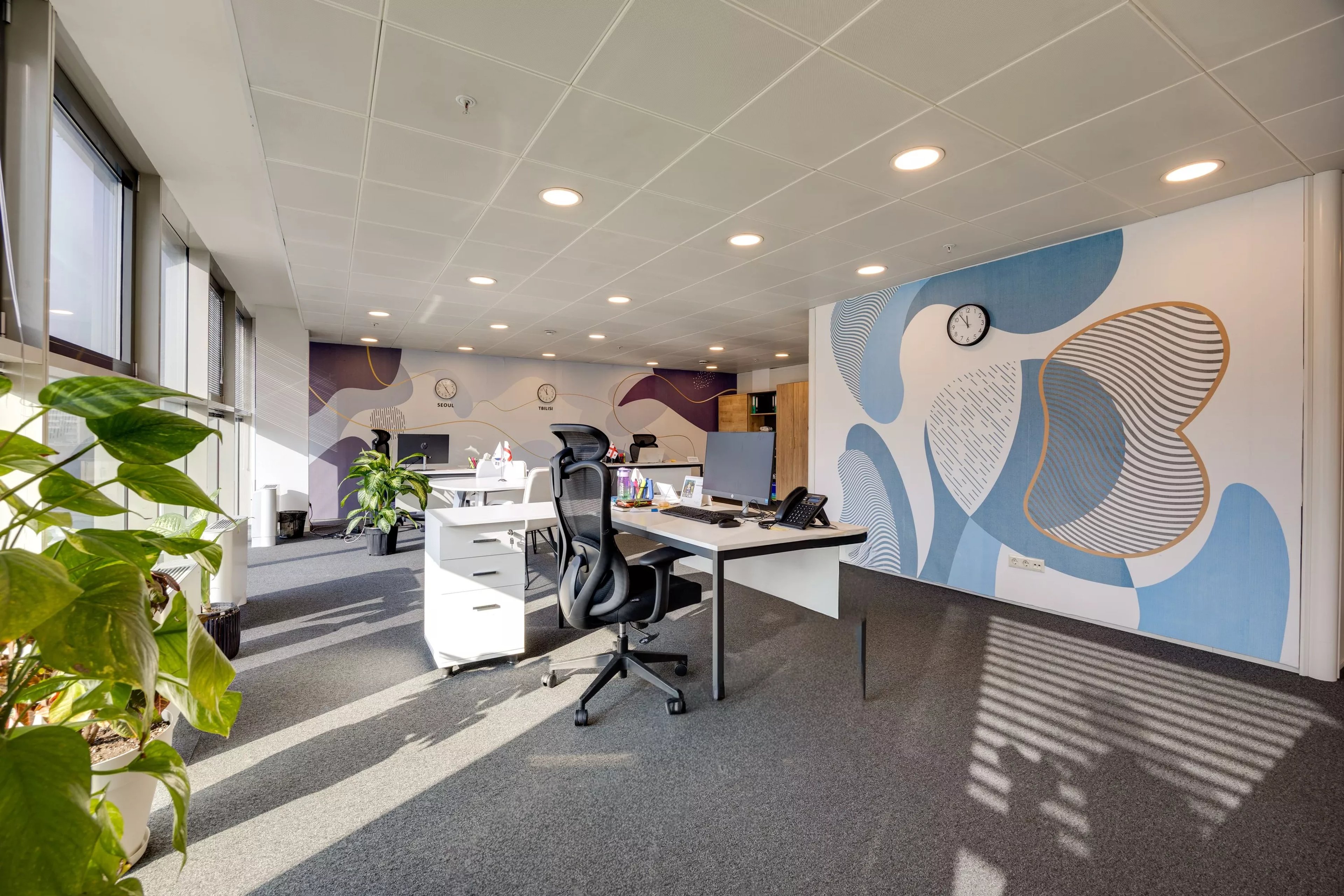 KOTRA open-plan office in the brand's blue-and-white palette with 4000K lighting and Seoul / Tbilisi wall clocks