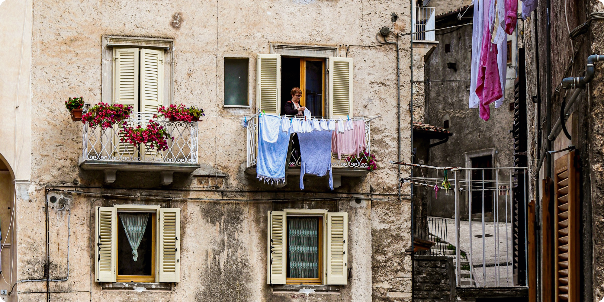A balcony with flowers and laundry on a stepped street in Scanno, Abruzzo