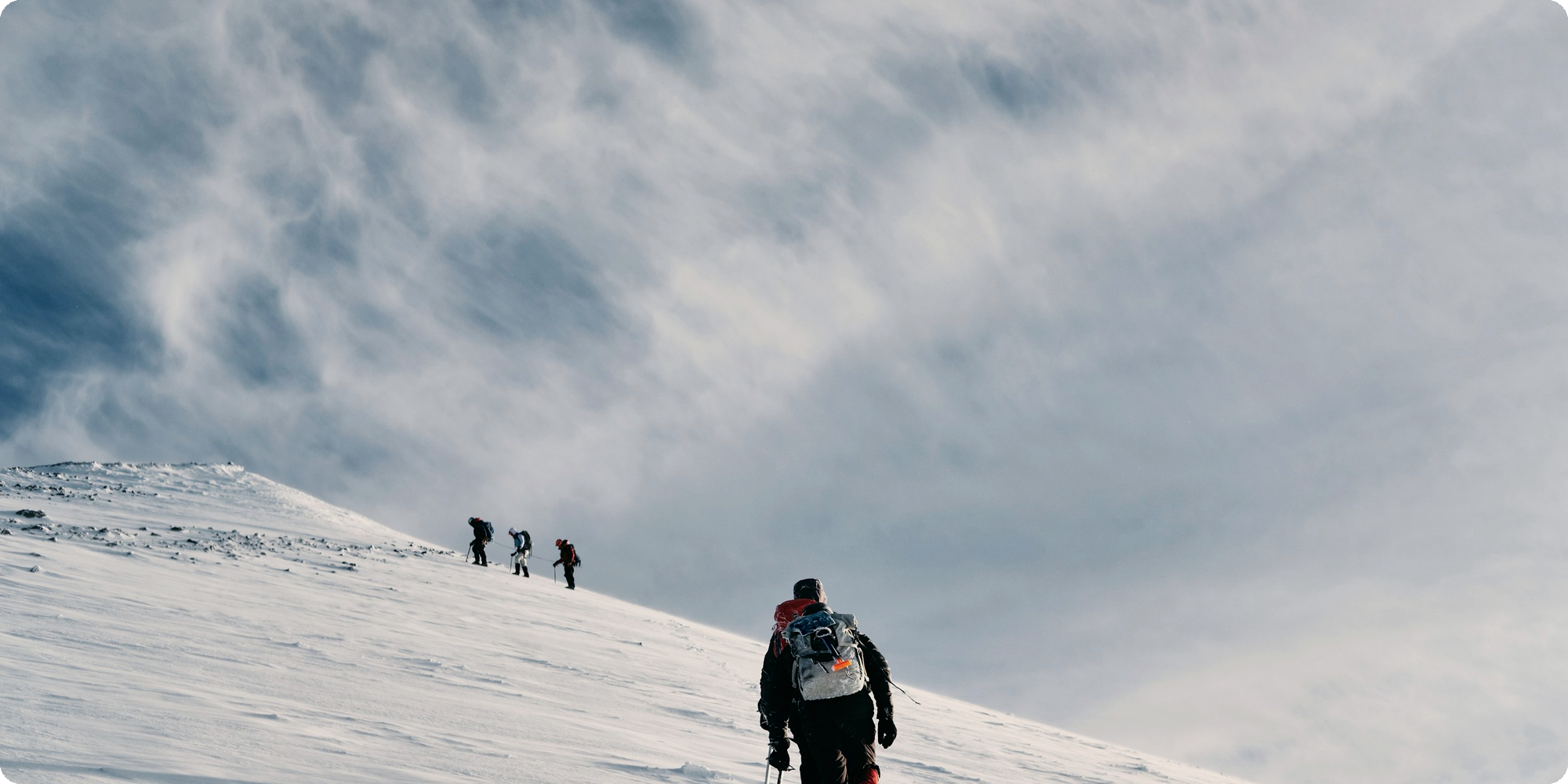 Climbers strung out across a vast snowfield below the summit