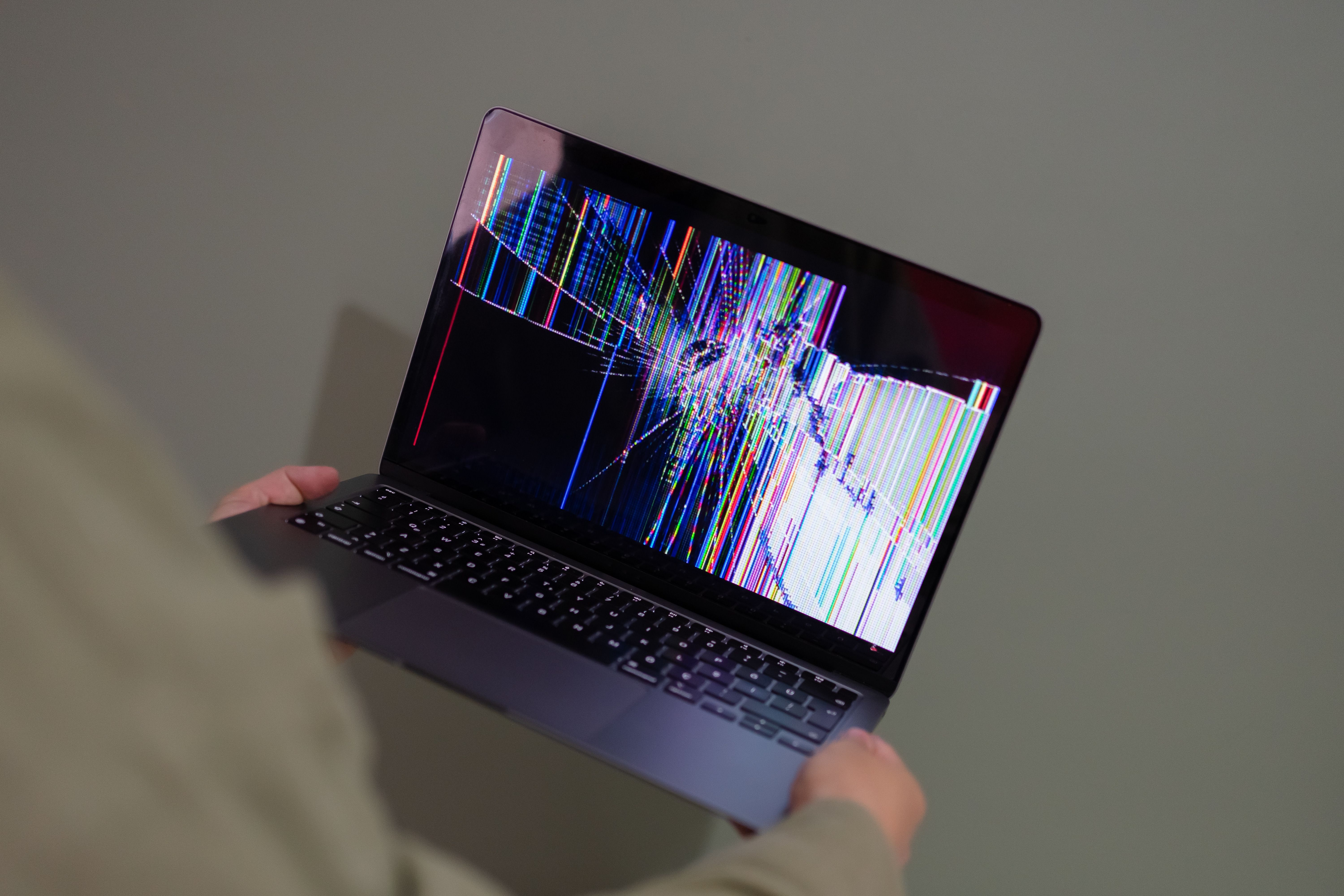 Close-up of a MacBook screen showing a dark pressure blotch near one edge while the aluminum lid looks undamaged