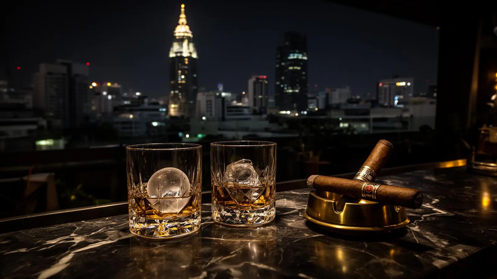 Two crystal whisky tumblers on a teak rooftop bar with the Buriram circuit floodlights in the distance