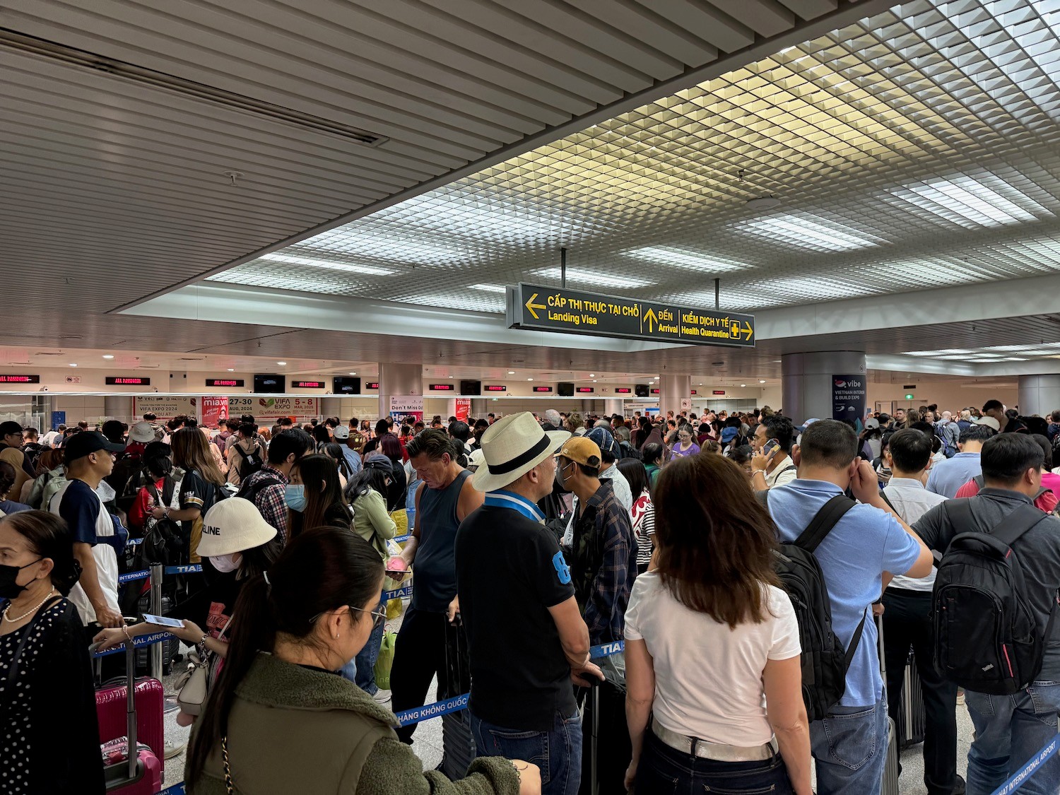 胡志明市新山一国际机场入境大厅，大批旅客在海关排队等候通关，指示牌清楚显示出入境及海关方向 / Win Royal Spa 皇家越式按摩
