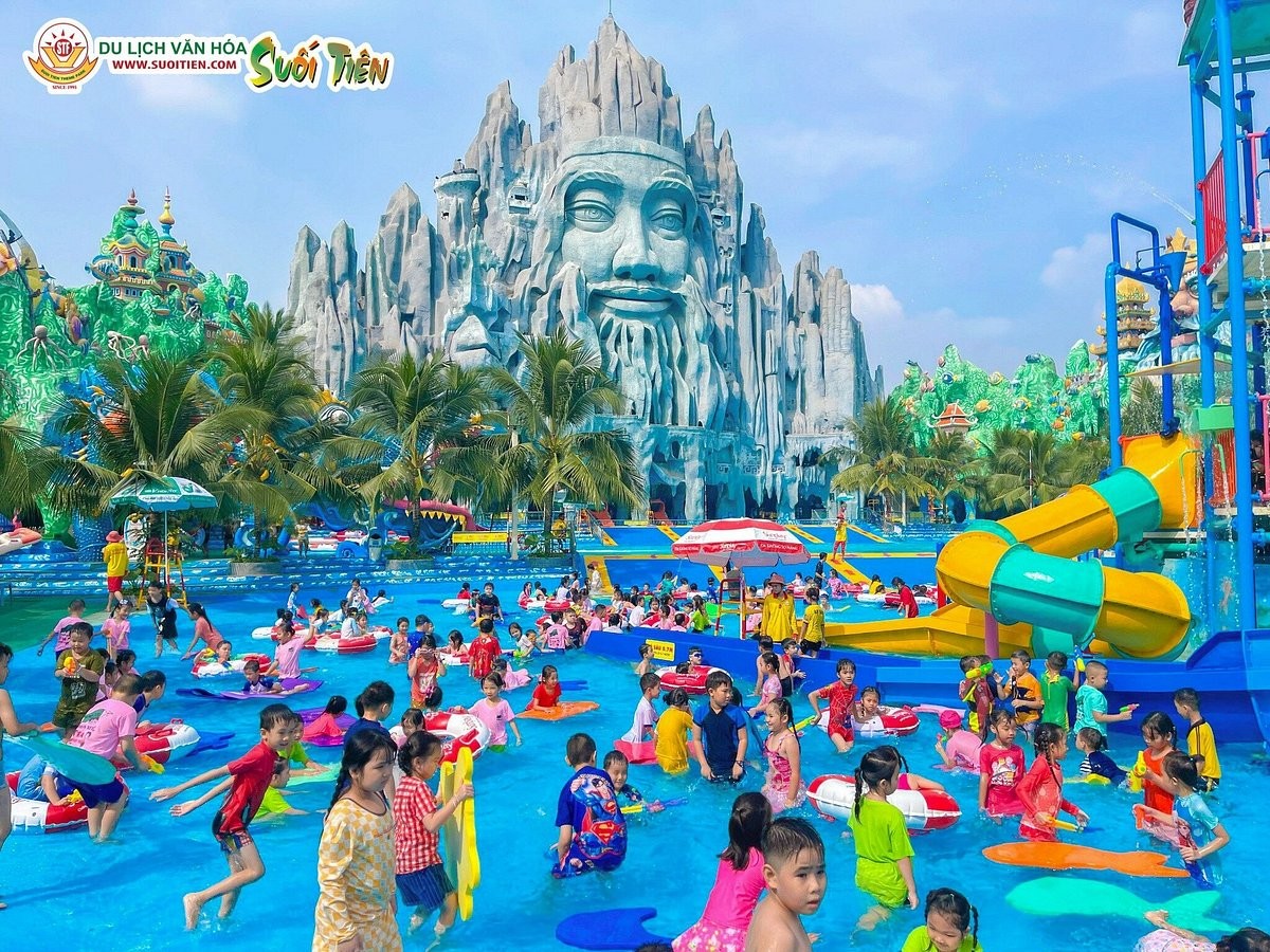 仙泉文化主题公园（Suối Tiên）水上乐园，背景有巨大石雕人脸，小朋友在水池中嬉戏，位于胡志明市守德市
