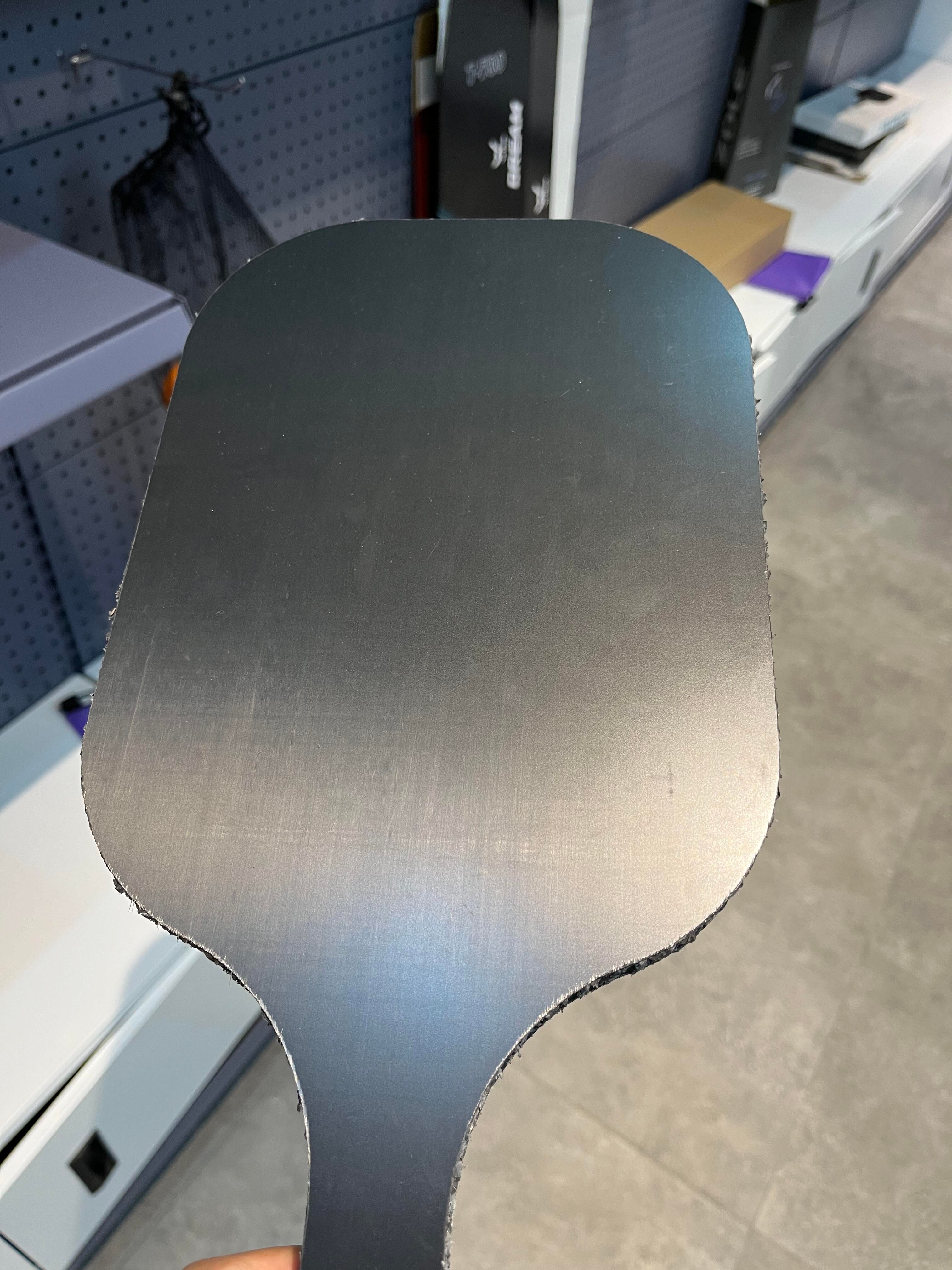 Plain unprinted paddle face held in front of production stock; no cleaning action shown