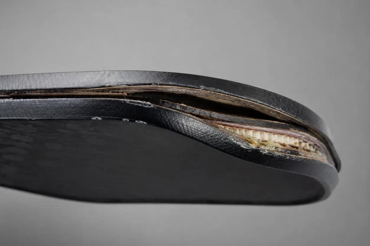 Side view of a composite pickleball paddle edge where the face laminate has lifted away from the honeycomb core