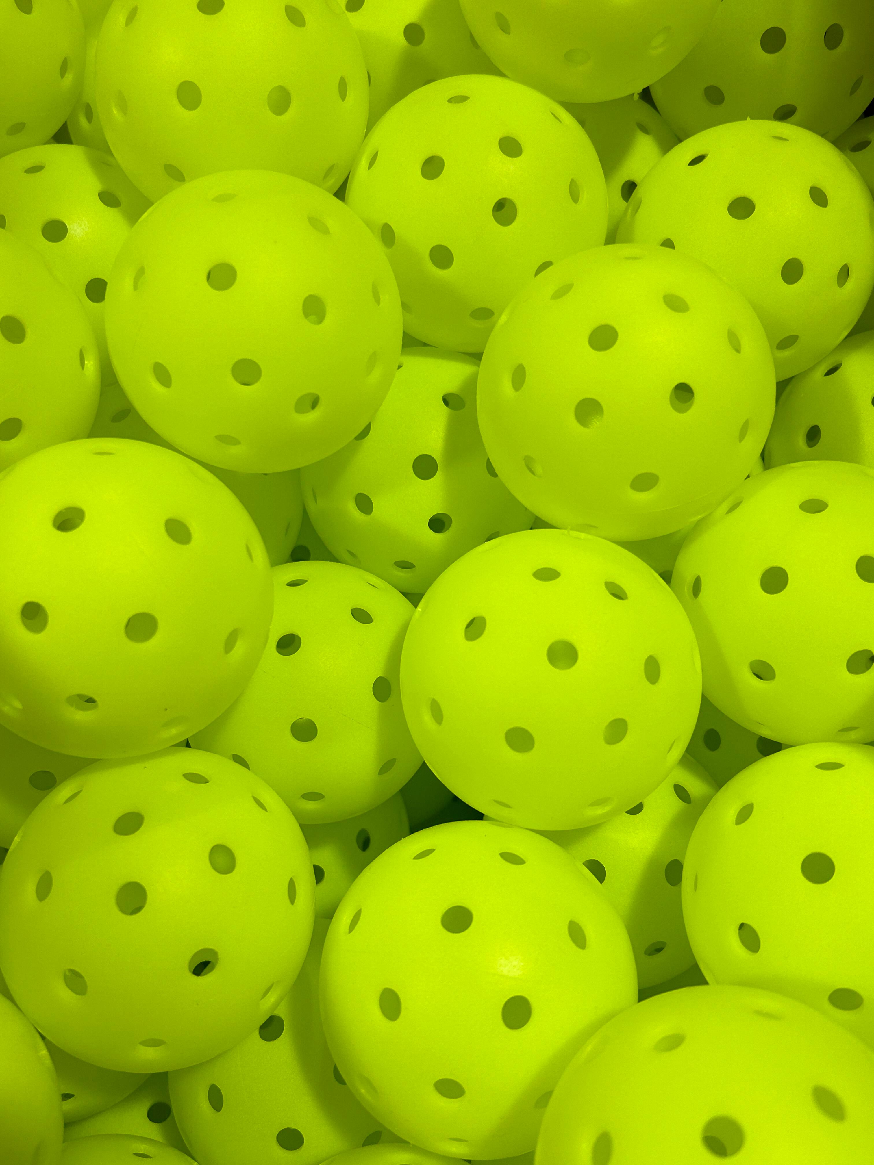 Close-up of finished neon-yellow 40-hole rotomolded pickleballs