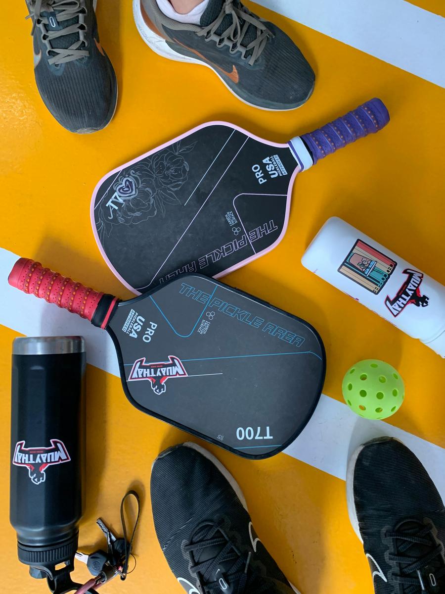 A row of pickleball paddles showing visible surface and edge defects lined up after sorting, illustrating the defective units a passing lot can still contain