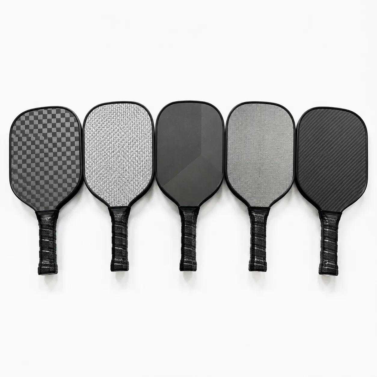 Five unbranded pickleball paddles laid side by side, each carrying a different woven face texture