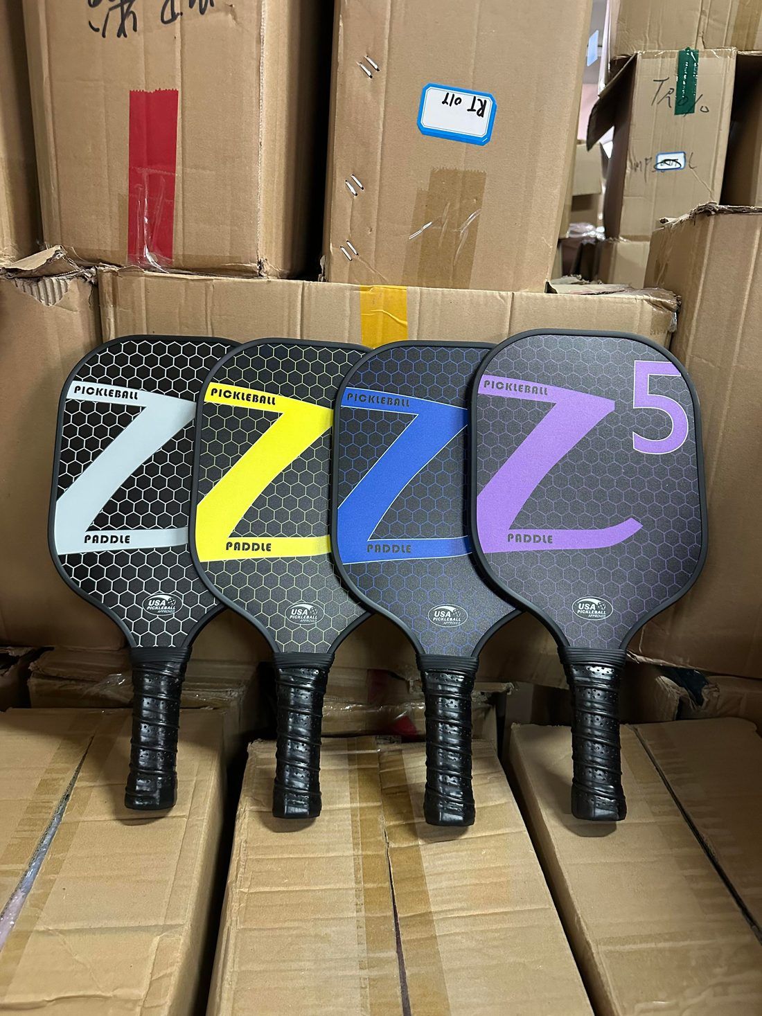 Textured carbon-faced pickleball paddles stacked at the factory before surface roughness inspection