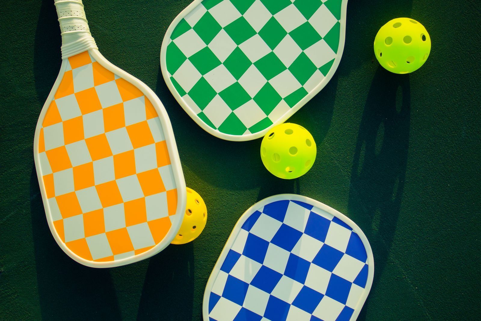 Rows of colorful pickleball paddles and balls arranged on an outdoor court — the crowded market a buyer actually faces