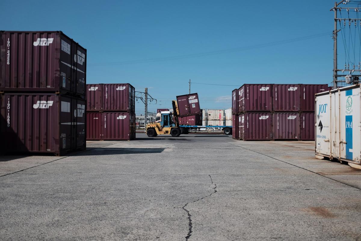 Container yard with a forklift loading a shipping container onto a trailer — the freight tier venue orders cross into past the break-even