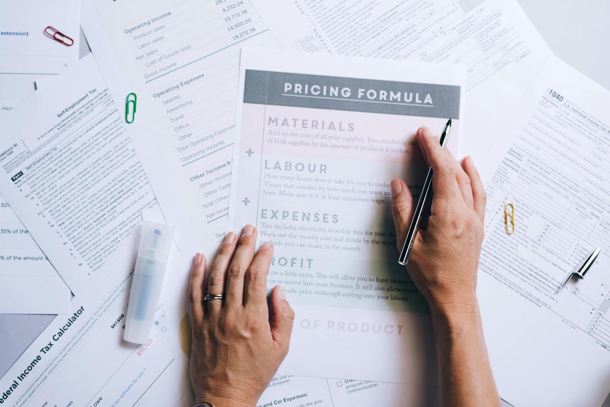 A supplier costing worksheet on a desk with a pen in hand, the quotation document that allocates freight and duty between seller and buyer