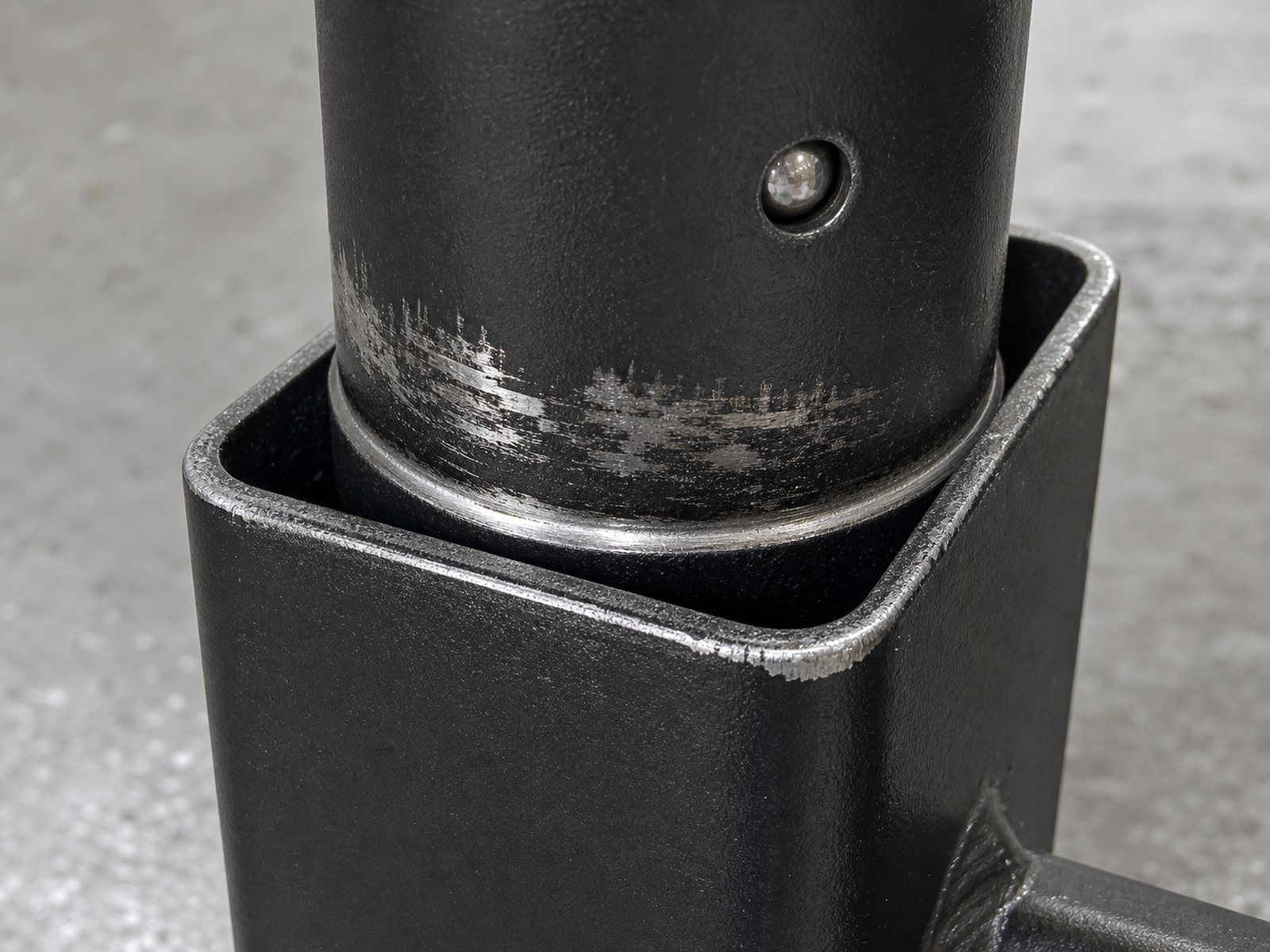 Close-up of a telescoping net frame joint showing coating worn to bare metal around the tube and a snap-button detent hole