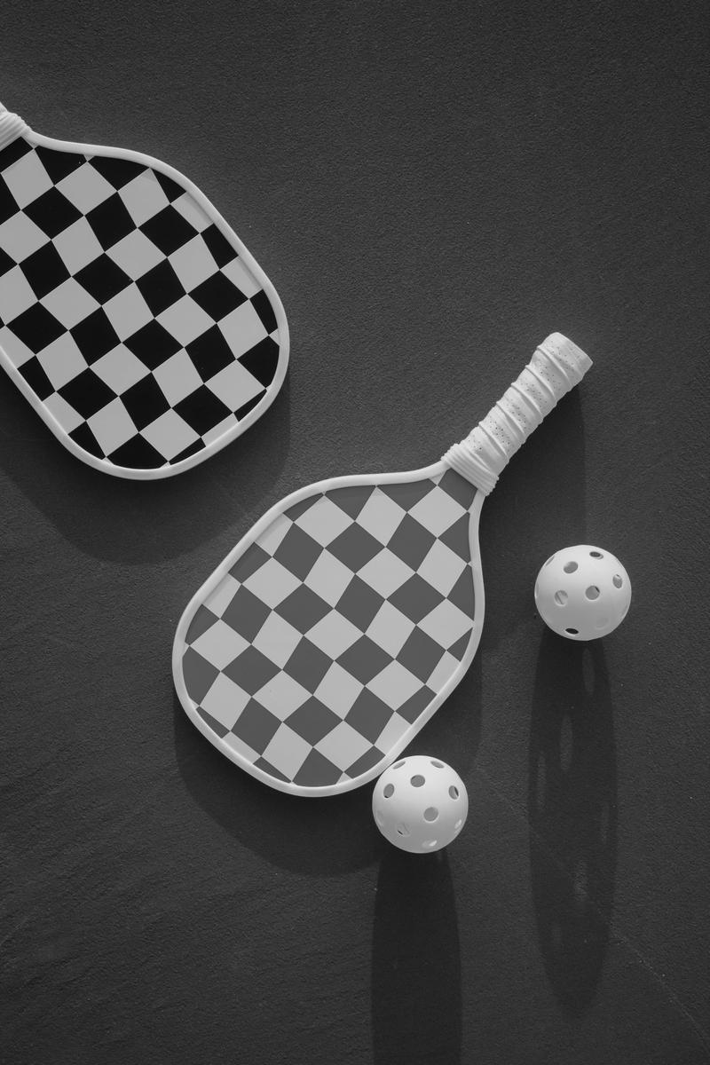 Hyper-realistic product photography, three professional pickleball paddles positioned on a high-tech testing bench in a clean industrial laboratory, precision measurement instruments and calibrated weights visible nearby, dramatic studio lighting with soft shadows, shallow depth of field focusing on paddle surface texture, modern B2B aesthetic, no text, no brand logo