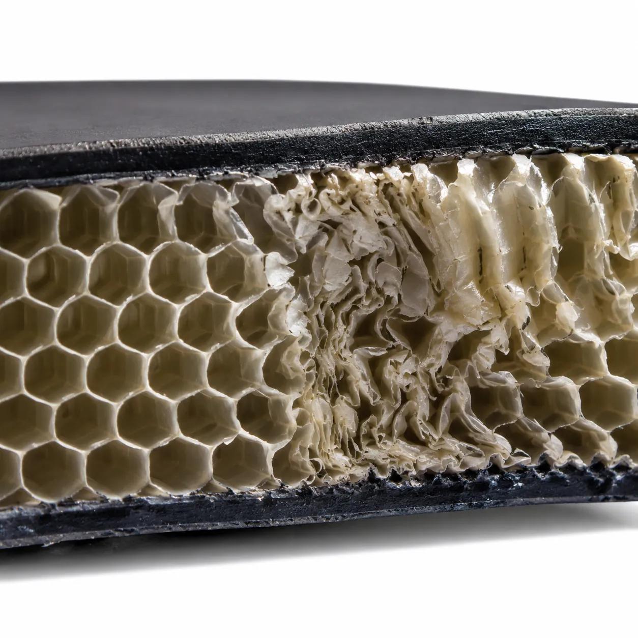 Hyper-realistic product photography, cross-section of a pickleball paddle honeycomb core showing collapsed cells from crushing, macro lens, bright studio lighting with sharp shadows, detailed polypropylene structure with visible density variation, no text, no brand logo