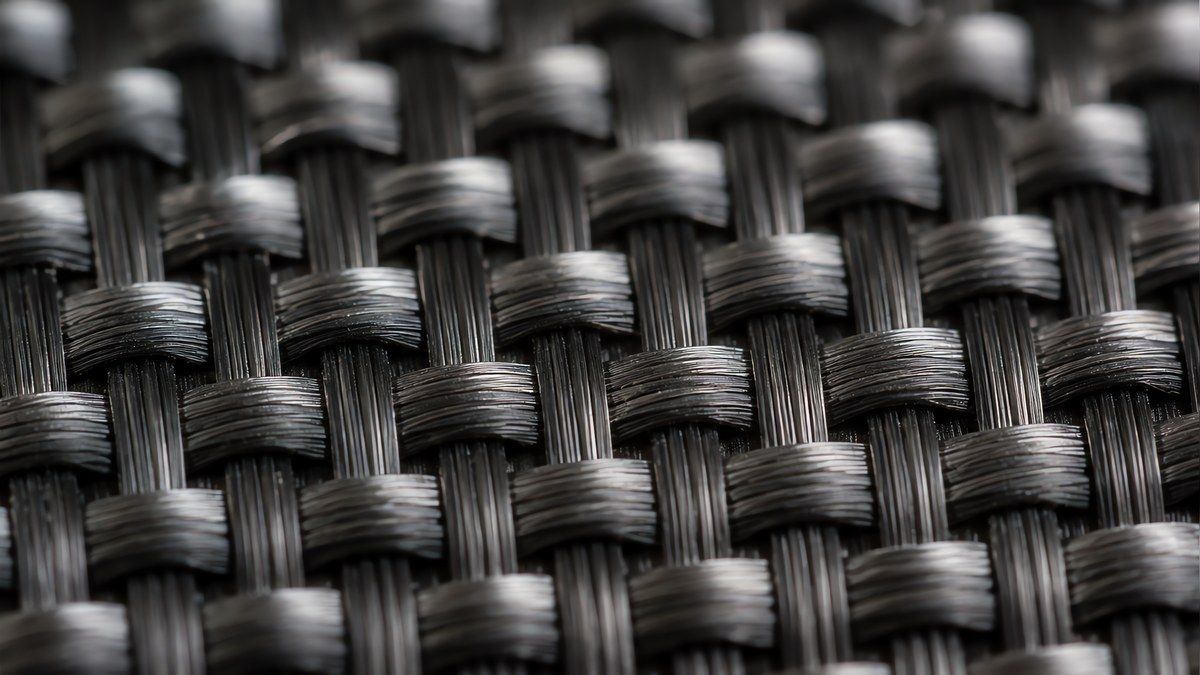 Extreme macro of a 3K plain weave carbon fabric showing individual tows crossing over and under in a tight checkerboard