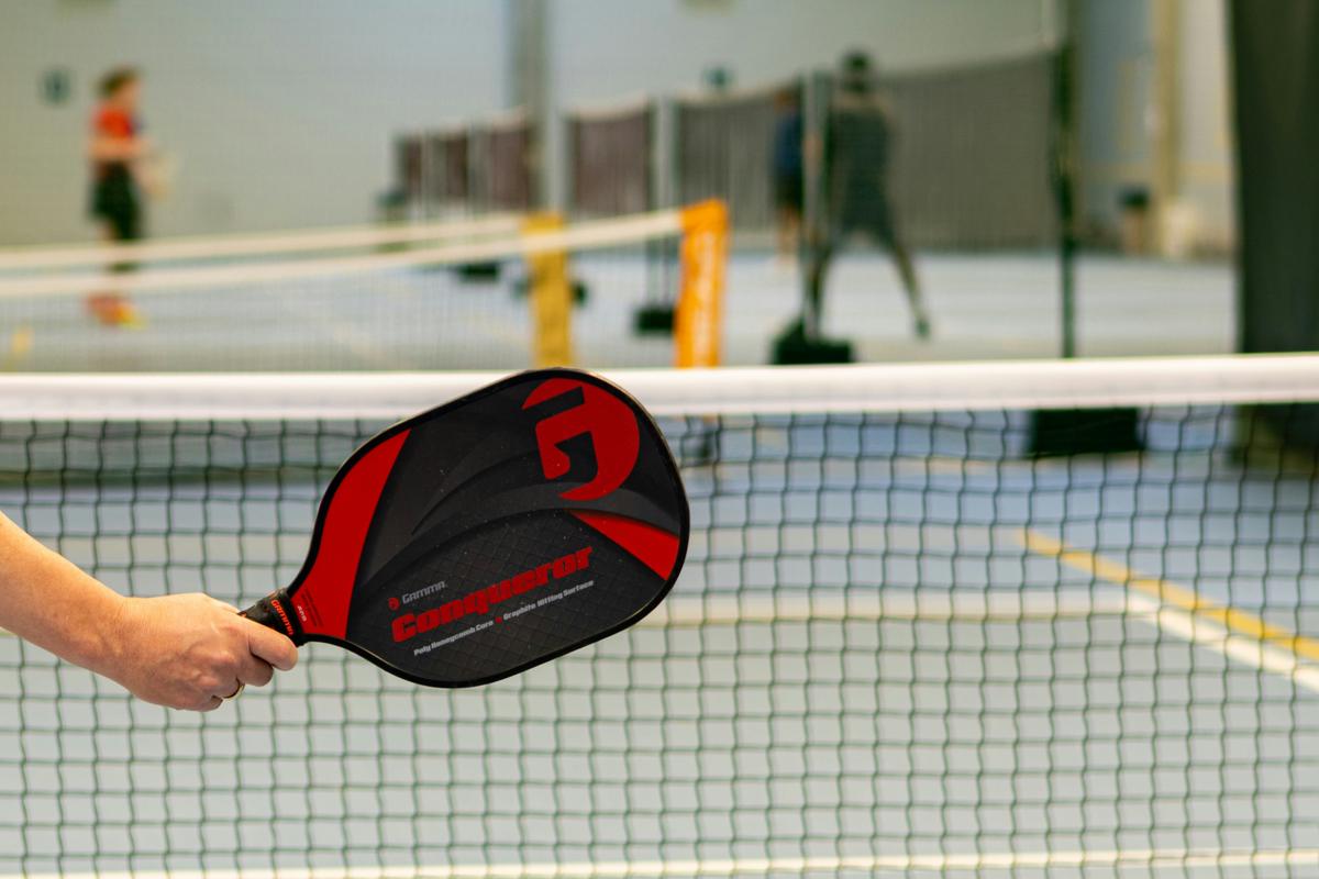 Hyper-realistic commercial photography, a pickleball paddle being carefully inspected under a magnifying lamp by gloved hands with a clipboard and quality checklist in the background, clinical bright lighting suggesting rigorous testing standards, tight crop on inspection process, no text, no brand logo