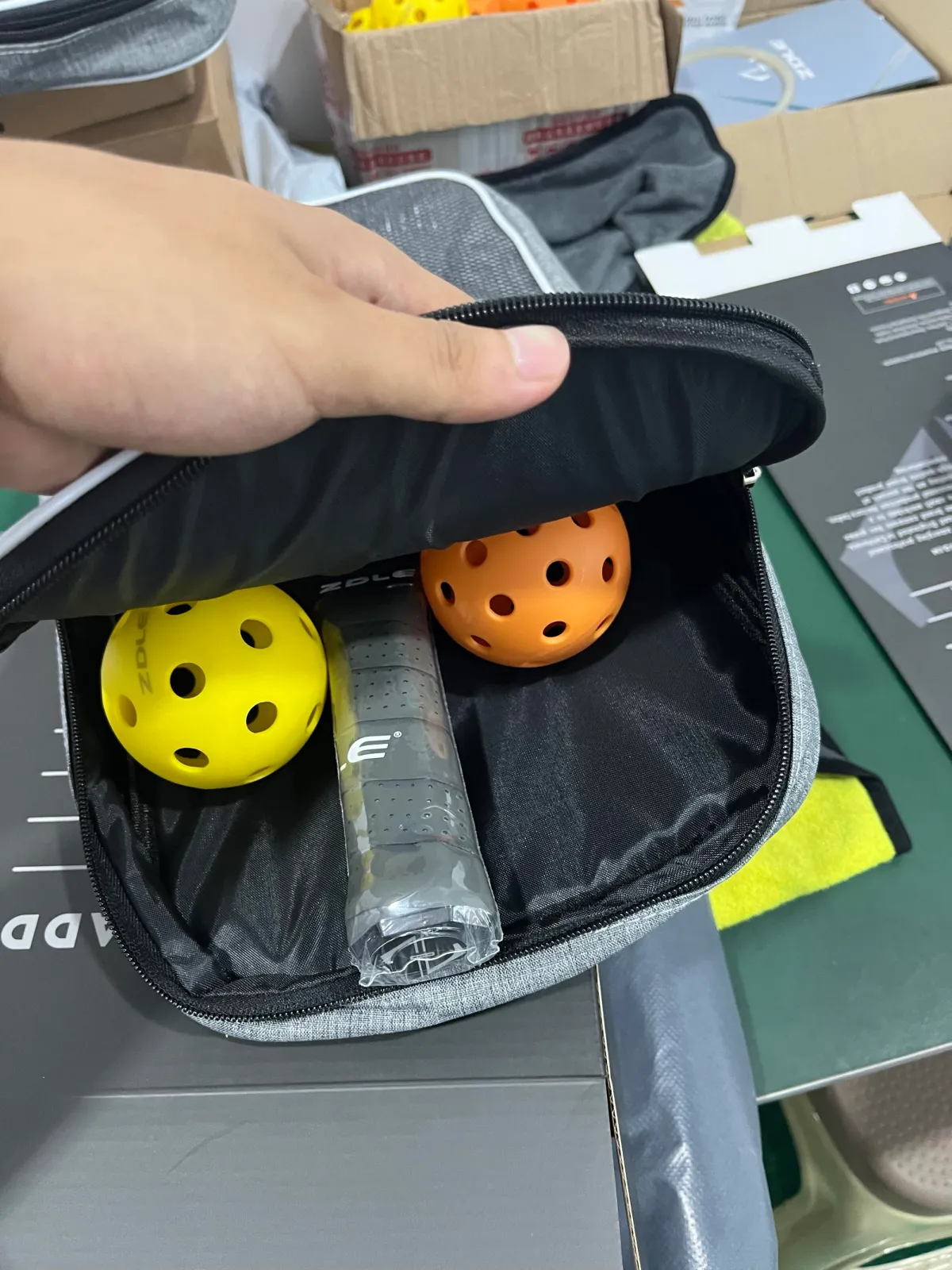 Open compact carry case holding a paddle and two pickleballs