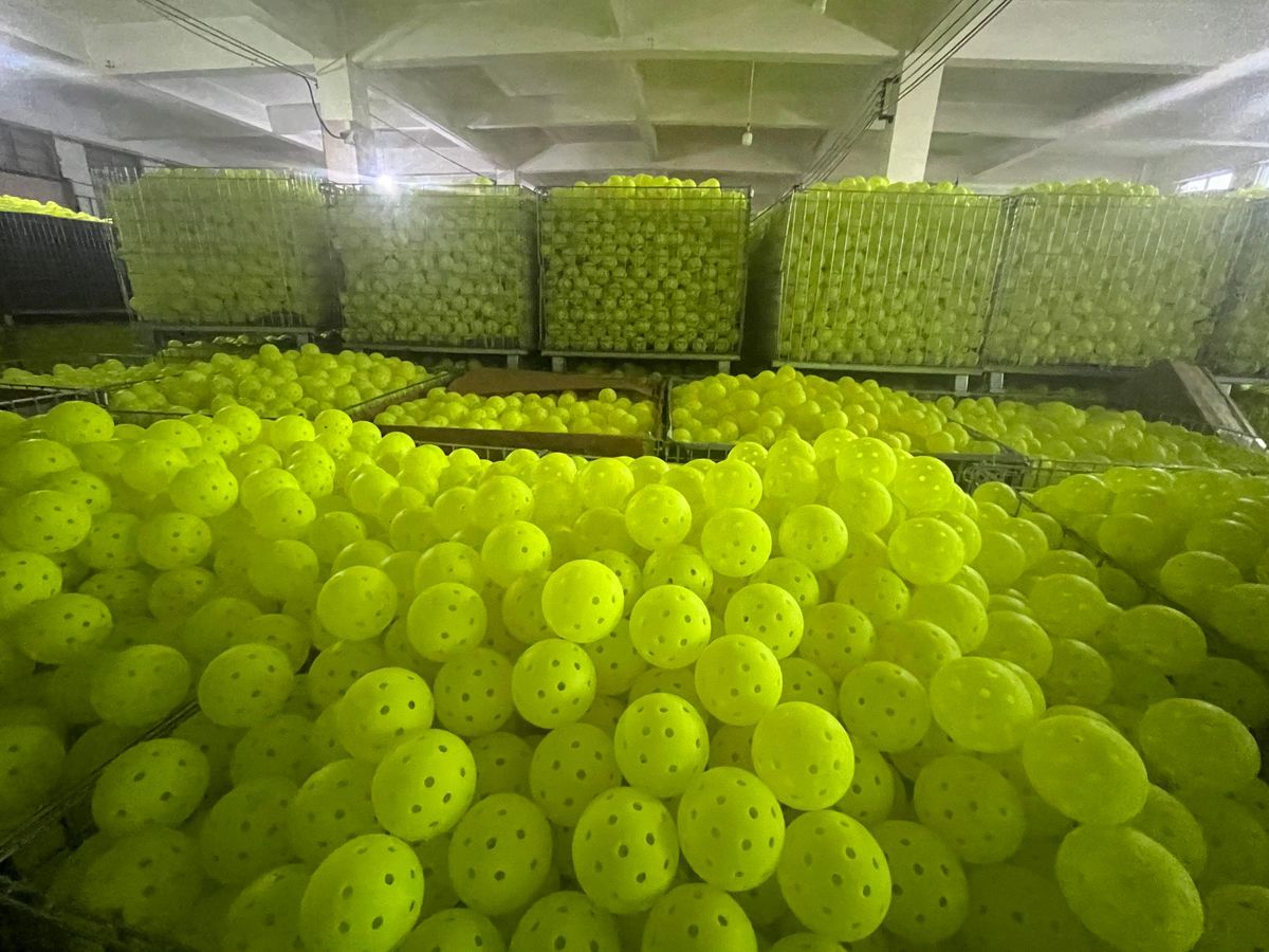 Thousands of 40-hole rotomolded pickleballs in bins on a source factory floor