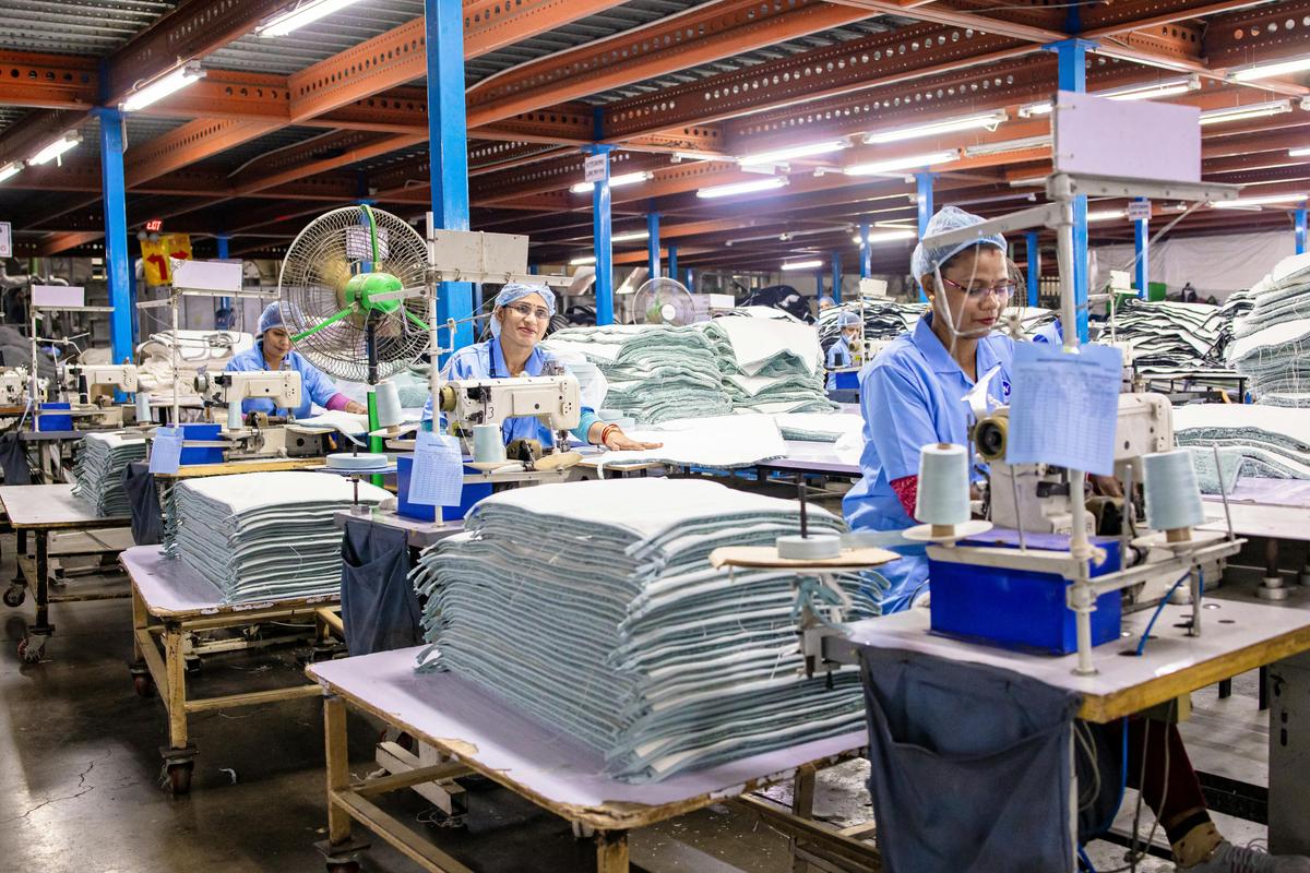 Two people comparing factory audit question sheets against production records at a pickleball OEM supplier