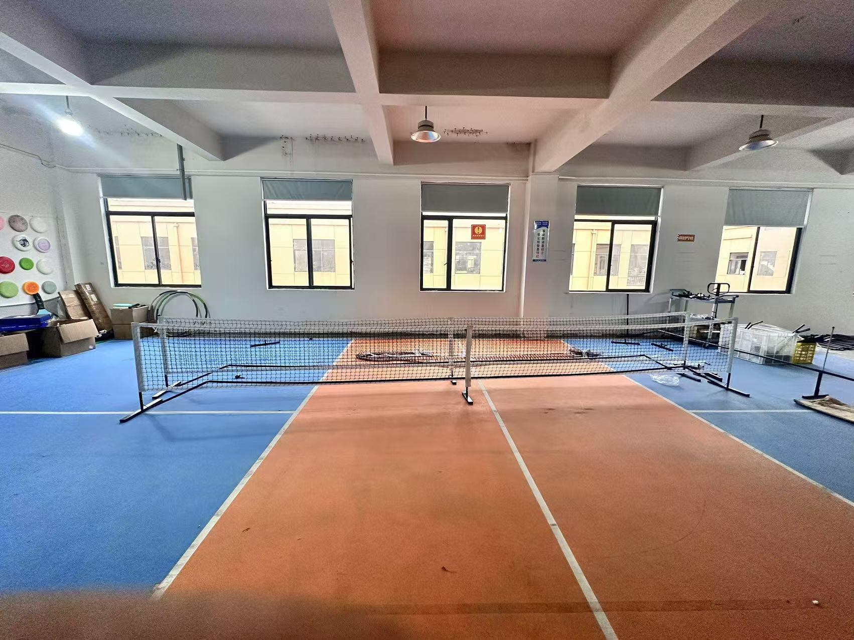 Blue-and-orange indoor court with windows and seating