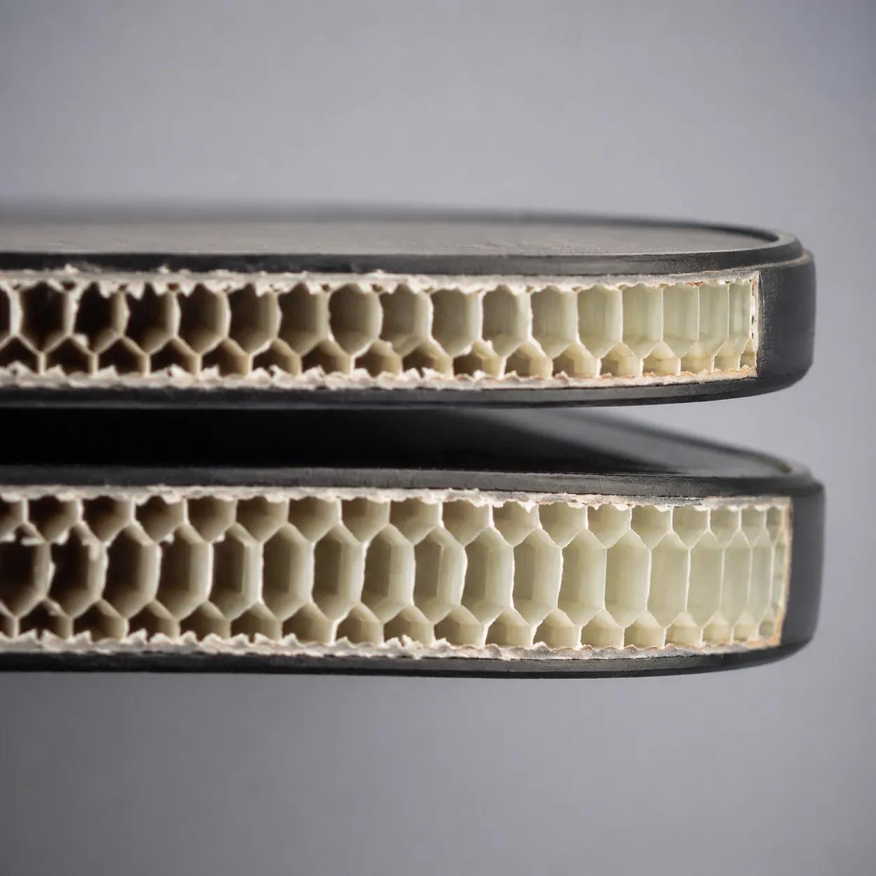 Hyper-realistic product photography, cross-section of two pickleball paddles showing 14mm and 16mm core thicknesses, detailed honeycomb cells visible, macro lens shot, neutral gray background, soft overhead lighting, no text, no brand logo