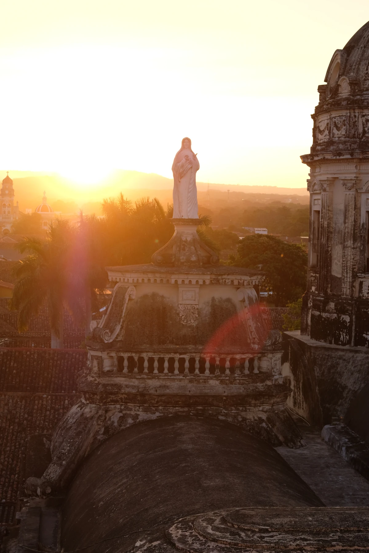 The silhouette of a colonial church and its domes against a brilliant sunset with sun flare