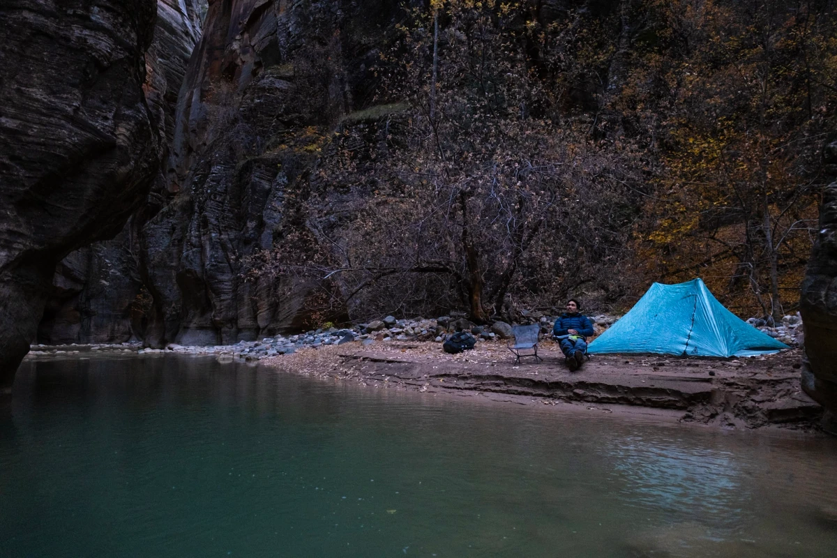 A backpacking tent pitched on a sandbar beside the river at a Narrows campsite
