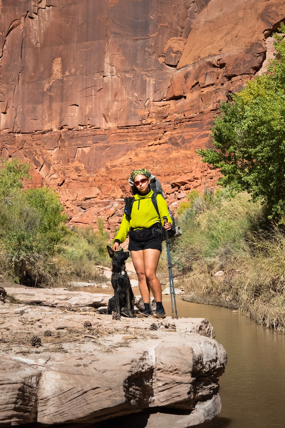 A backpacker and dog resting on a rock ledge beside the river
