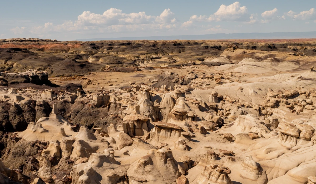 Wide view over the hoodoo basin of Bisti Badlands under a cloud-streaked sky