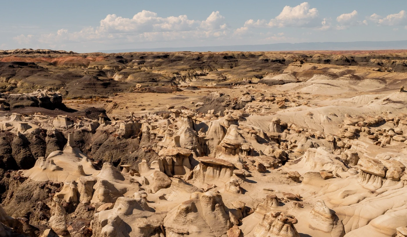 Wide view over the hoodoo basin of Bisti Badlands under a cloud-streaked sky