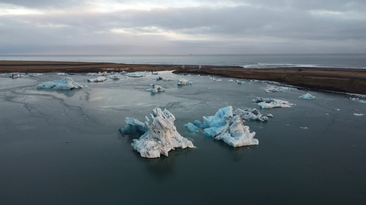 Aerial view of icebergs floating in the grey Jökulsárlón glacier lagoon under an overcast sky