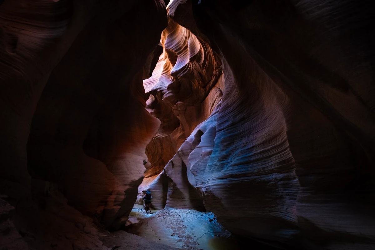 A tiny figure dwarfed by a vast curving slot-canyon chamber