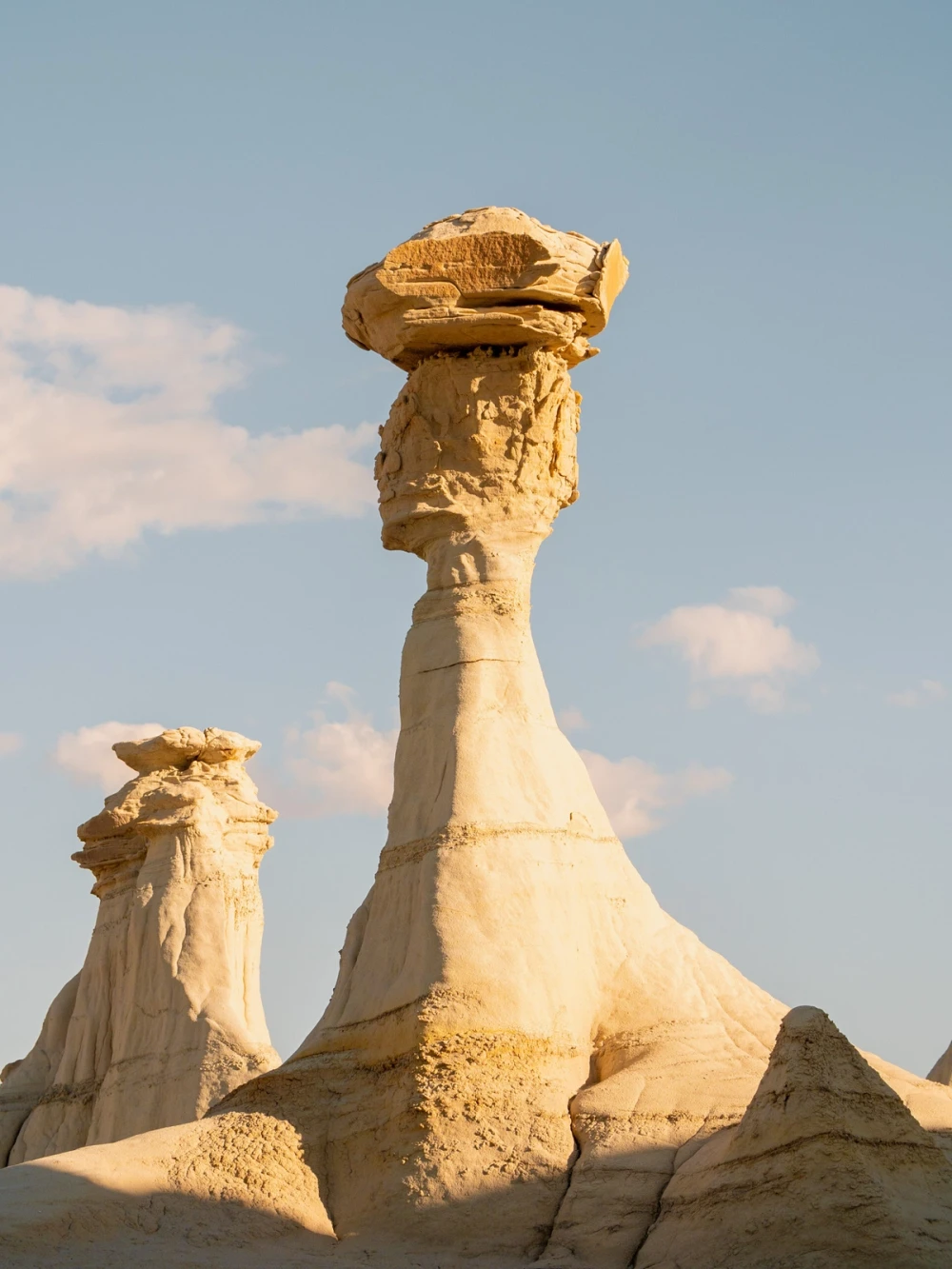 Two capped hoodoos standing against a blue sky at golden hour