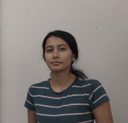 Portrait of a person with their hair tied back wearing a green and shite striped t-shirt