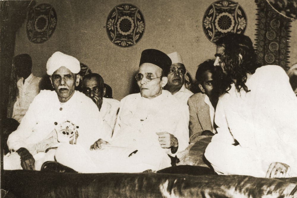 Three men seated cross-legged side by side.