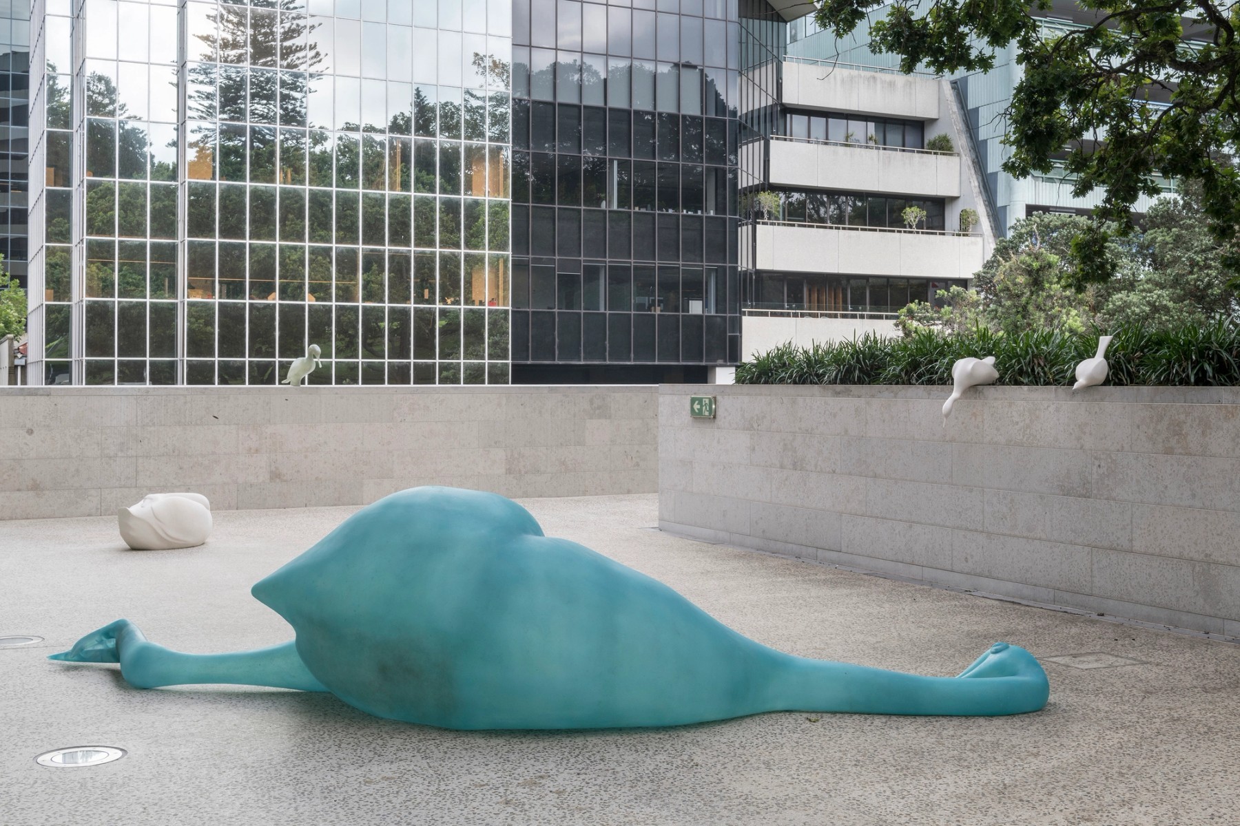 a turquoise body of a large bird on its side laying on the ground