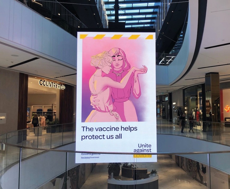 A poster with the a pale pink drawing of two people in a close embrace, with the text "The vaccine helps protect us all"