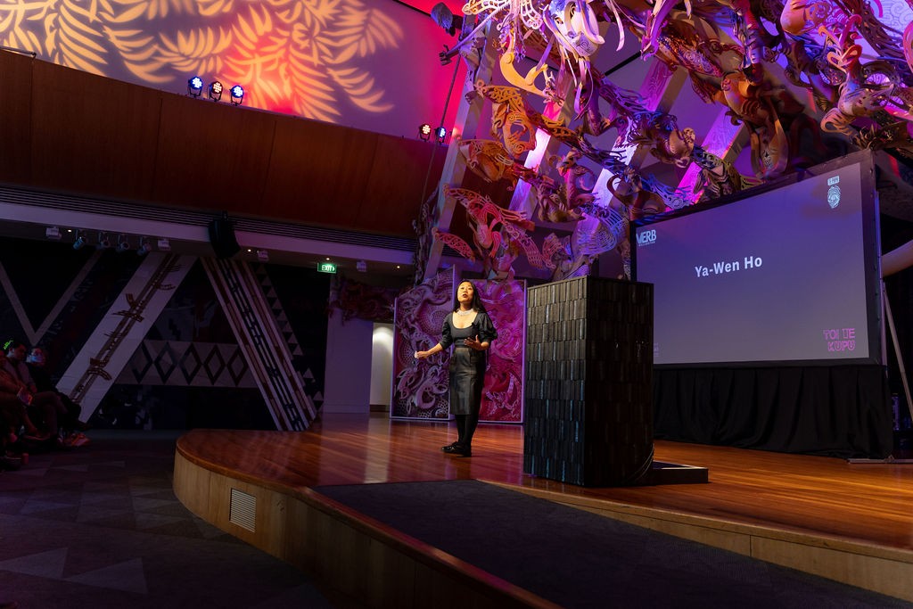 A person on stage speaking.