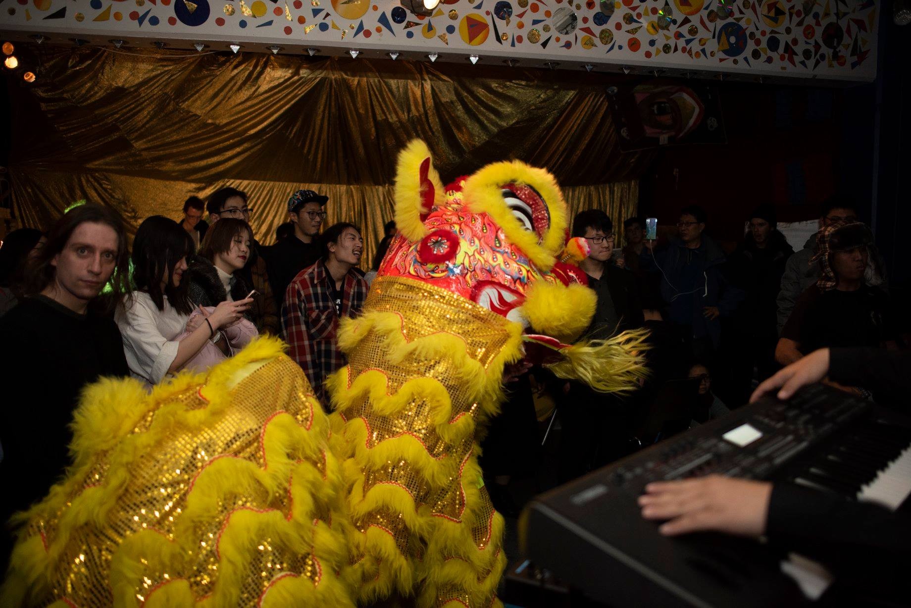 Lion dance performance in a busy crowded room packed with audiences and band playing on the side
