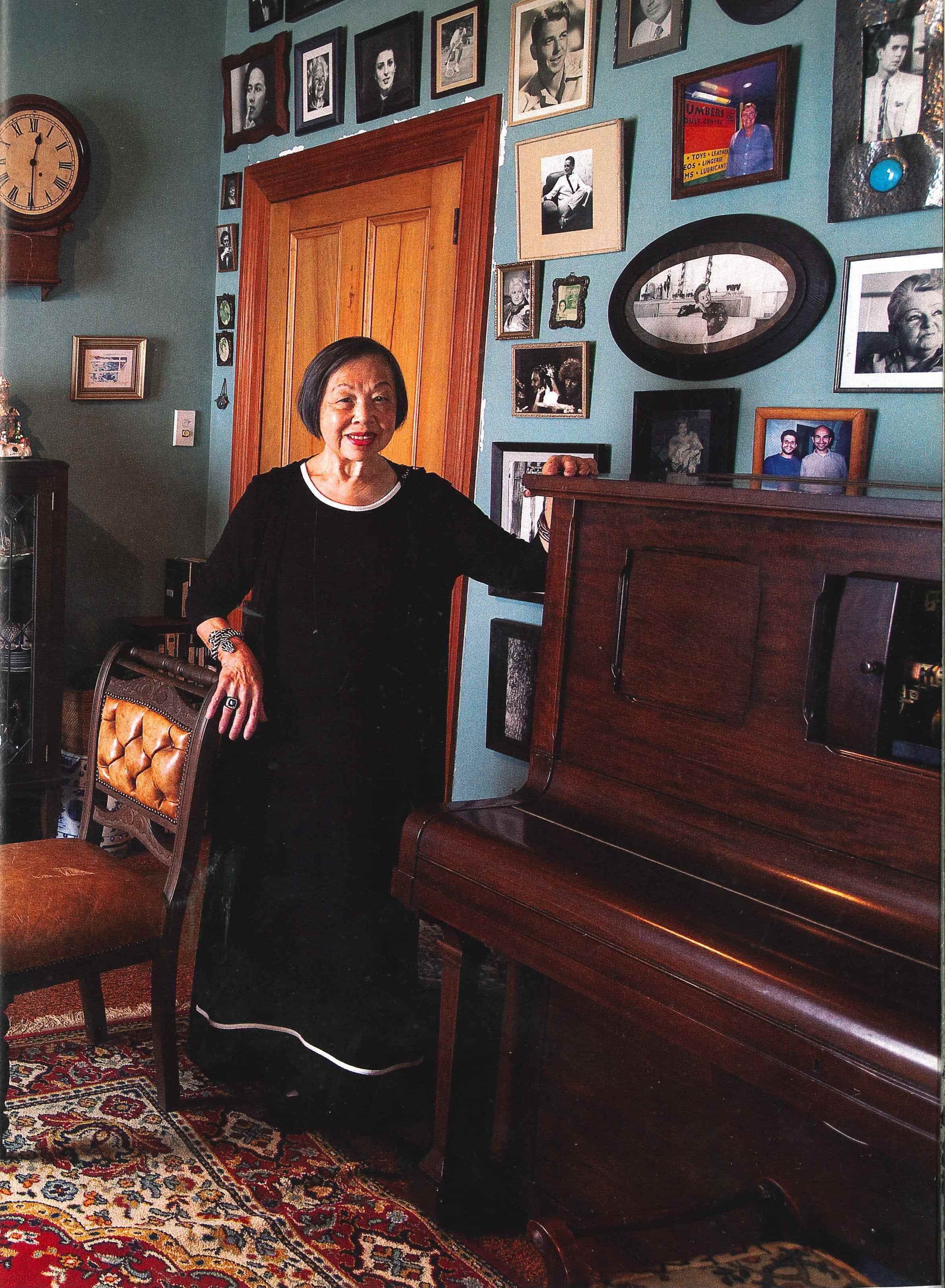A woman in a room with a piano and framed photographs on the wall