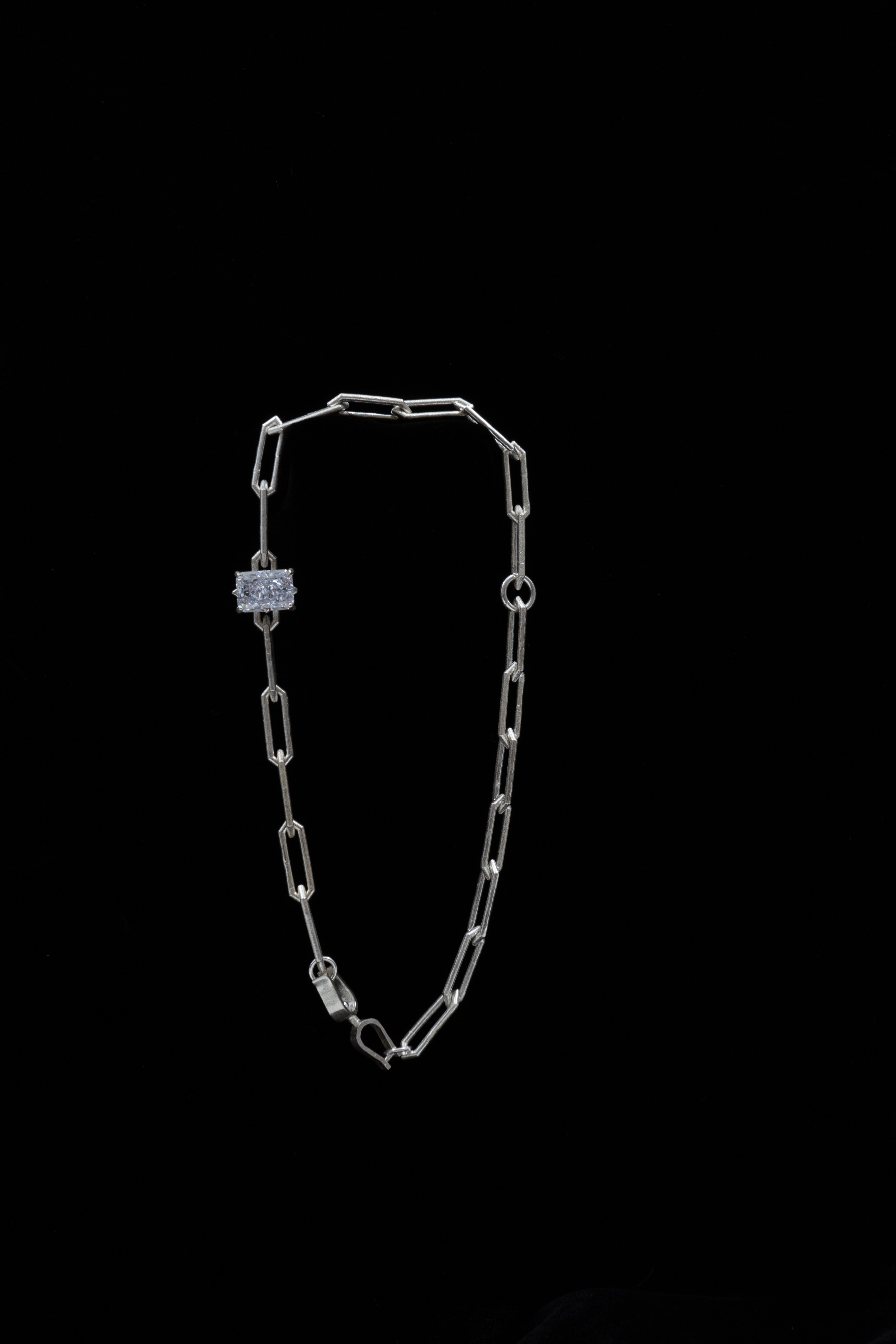 A short silver chain with hexagonal tips and longer sides, embellished with a rectangular diamond