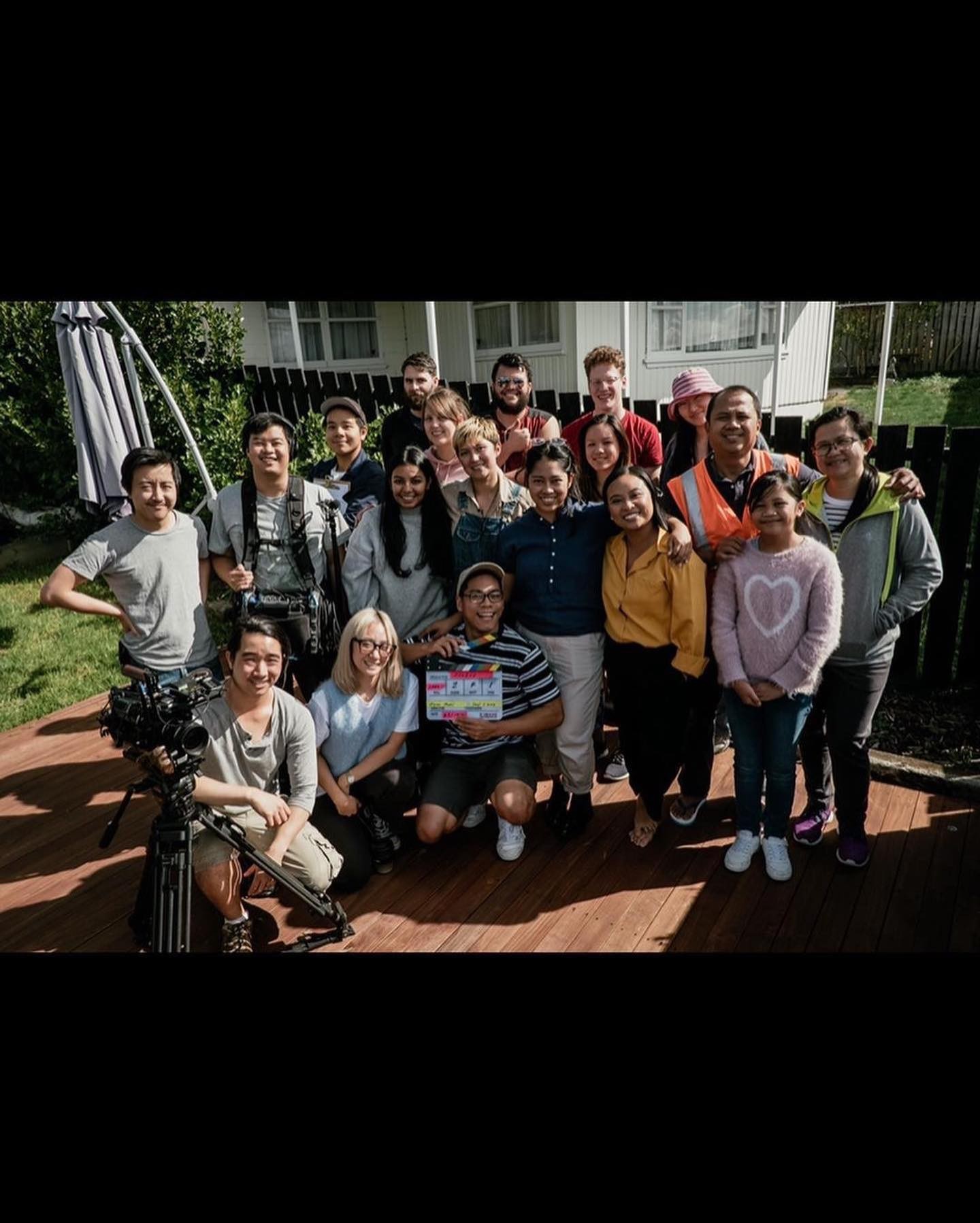 Many people posing for the camera on the deck of a house