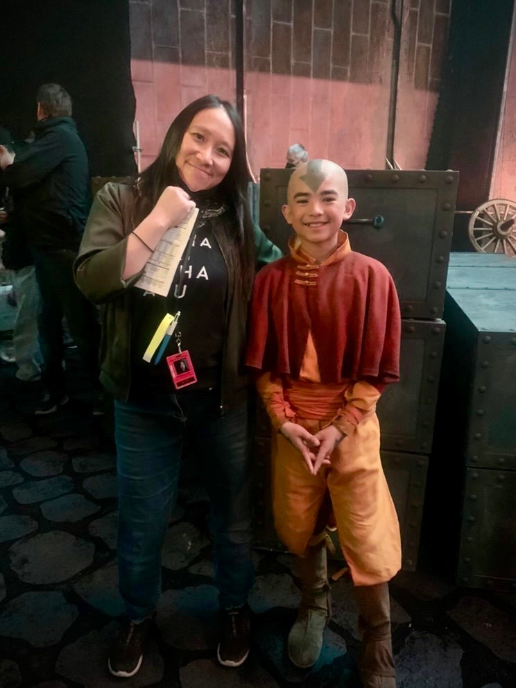 A Chinese woman posing with a young man in a red poncho and orange pants