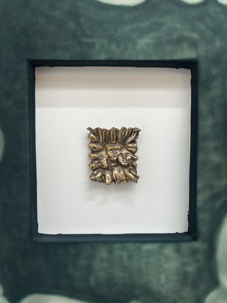 A gold sculptural object in a frame