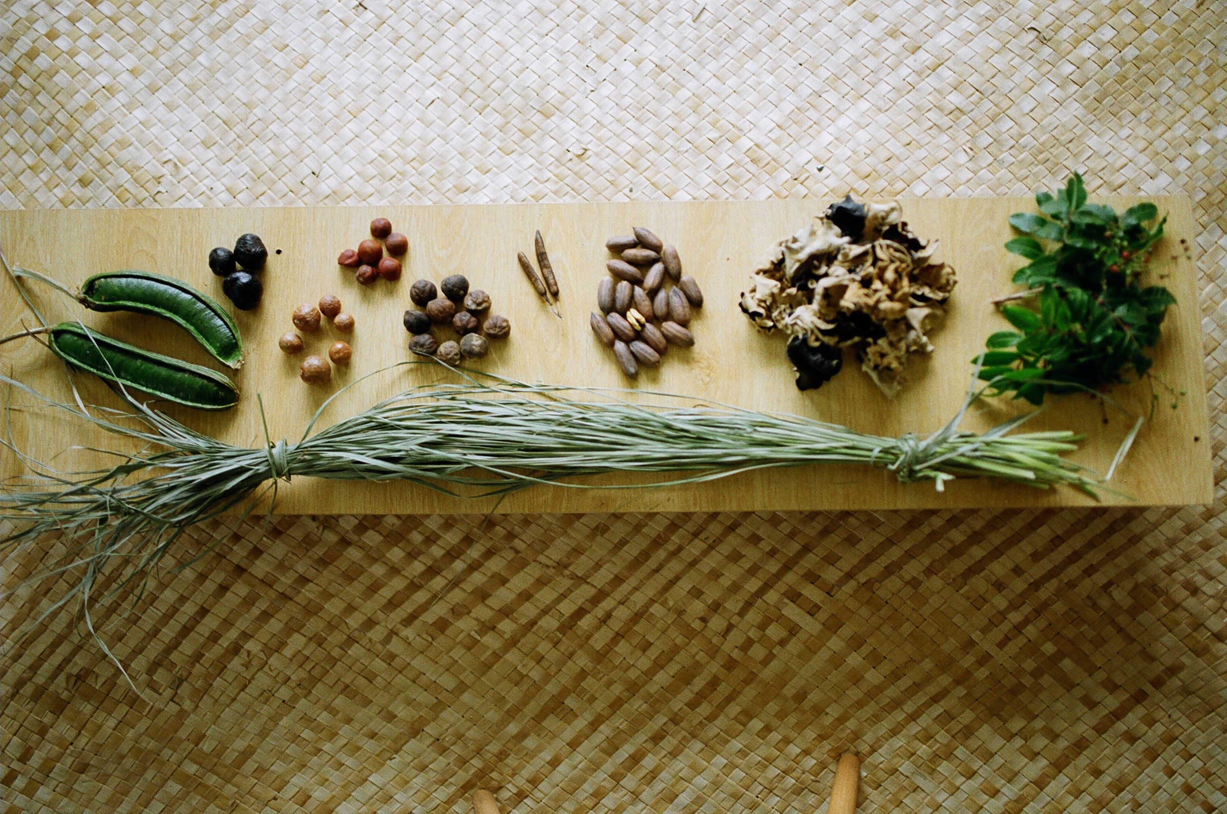 Various seeds and herbs on a low table placed over a woven mat