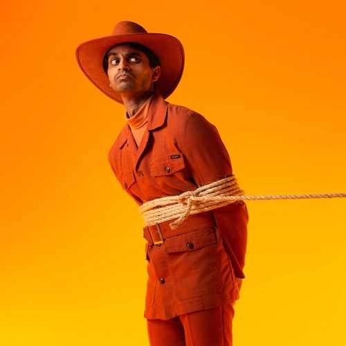 A man in an orange cowboy suit is held by a lasso