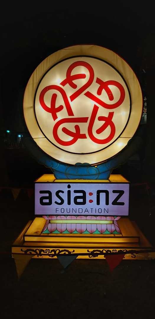 A fabric lantern featuring the Asia NZ Foundation logo is illuminated in the night.