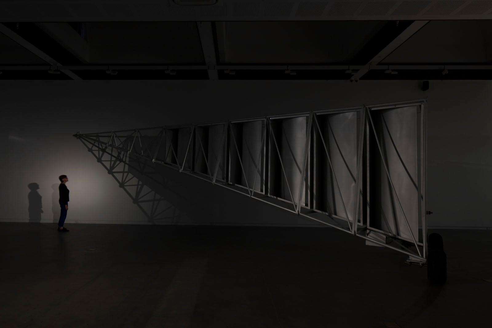 A gallery visitor is dwarfed by a scaffold structure.